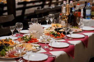 Elegant Banquet Table Setup with Assorted Delicacies, Wine Bottles, and Fine Glassware on Red and White Checkered Tablecloth