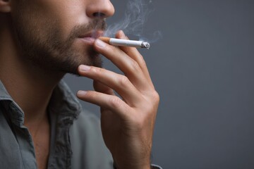 Obraz premium Young caucasian male smoking cigarette with focus on hands and smoke