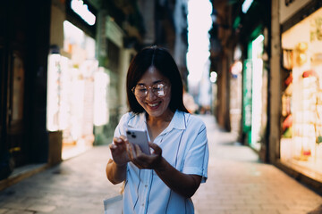 Smartphone-savvy woman exploring notifications in bustling city street, symbolizing mobile tech integration, everyday flexibility, and seamless connectivity in digitally enhanced routines. © BullRun
