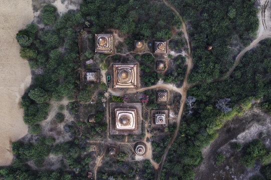 Aerial view of temples rise majestically from the lush greenery, their ancient brickwork glowing softly in the golden light, Old Bagan, Mandalay Region, Myanmar.