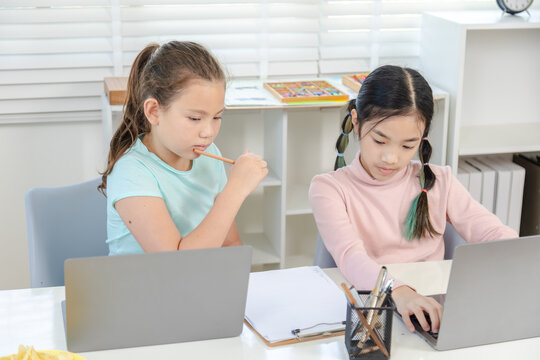 Education learning children home technology concept shows two girls studying together with laptops, teamwork and digital skills in modern private education environment, generation alpha lifestyle