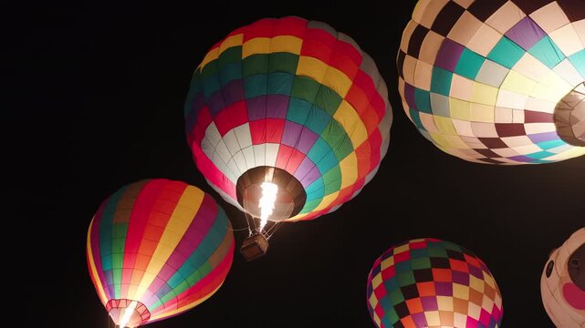 colorful hot air balloons glowing against the dark night sky