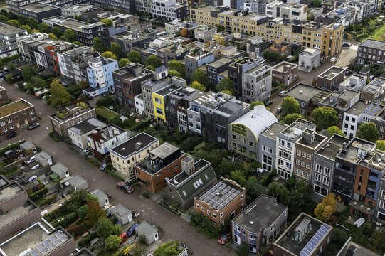 Aerial view of colourful townhouses and apartment blocks interspersed with verdant trees, creating a vibrant urban mosaic, IJburg, Amsterdam, Netherlands.