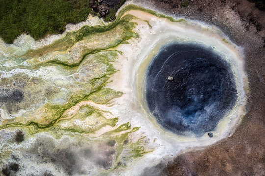 Aerial view of the geothermal hot spring framed by vibrant green algae and mineral deposits, creating a surreal landscape, Hveravellir, Hunabyggd, Iceland.
