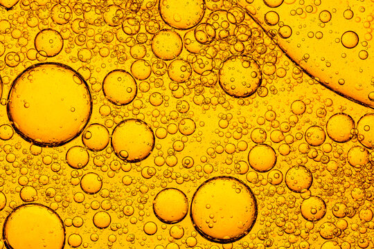 Golden Oil Bubbles in Water Macro Abstract Background,A detailed macro shot of golden oil droplets of various sizes floating in water, creating a beautiful abstract pattern with liquid texture.