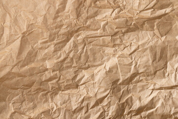 Obraz premium Crumpled brown kraft paper background macro,High-angle view of a sheet of crumpled brown kraft paper with heavy creases and wrinkled texture. This vintage-style aesthetic background is perfect.