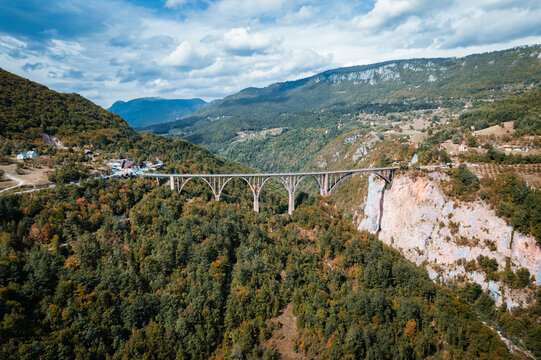 Aerial view of the majestic Durdevica Tara Bridge gracefully spans the deep Tara River Canyon, amidst a tapestry of autumnal forests, Zabljak, Opstina Pljevlja, Montenegro.