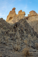 Landscape with whimsical rock formations and dry vegetation against sky