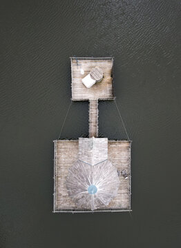 Aerial view of a rustic wooden structure with a small tower, standing starkly against the dark water, Joncherey, Bourgogne-Franche-Comte, France.