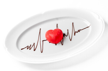 A red heart-shaped dessert with a chocolate EKG line on a white plate, perfect for Valentine's Day, anniversaries, or health-related concepts