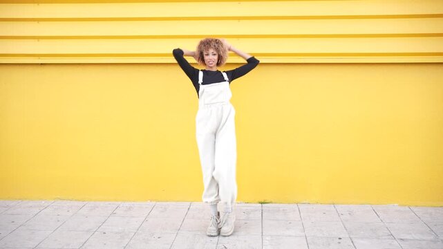 A Stylish Young Woman Posing Confidently Against a Bright Yellow Wall, Radiating Attitude