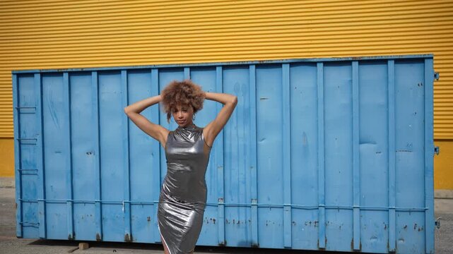 A stylish model confidently posing near a vibrant and colorful urban container backdrop
