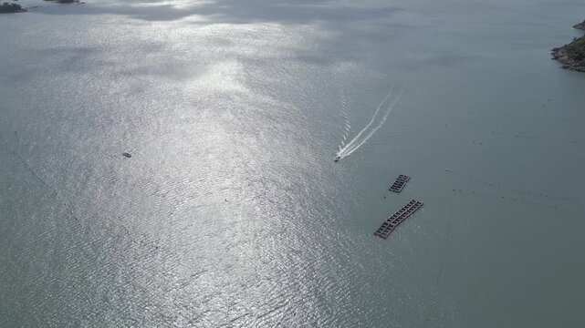 Aerial static view of a boat cruising on the sea with bright sunlight reflection