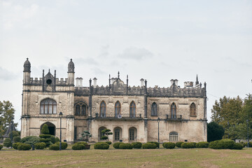 Fototapeta premium Castle ruins in a wide lawn setting, a historic stone building with arched windows and ornate battlements, creating a dramatic timeless landscape.