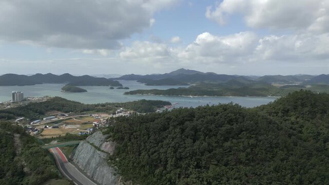 Aerial dolly shot of a scenic coastal road and lush green islands in Jindo, South Korea