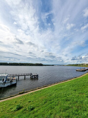 Obraz premium River pier and boat with wide cloudy sky