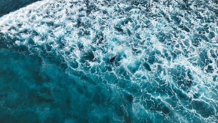 Fototapeta premium Surfer Swimming Amid White Ocean Foam in Deep Blue Sea