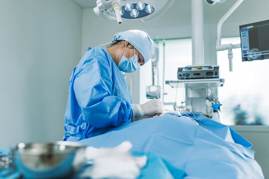 Female surgeon, performs a medical procedure in a modern operating room with professional medical equipment and teamwork to ensure safety.