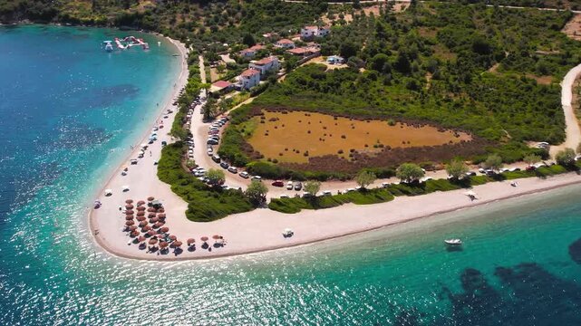 Aerial Cinematic Orbit of Agios Dimitrios Beach Alonissos &mdash; Picturesque Boat near Shoreline with Top-Down Drone Reveal of Sandspit Tip and Sunbeds, Sporades Greece
