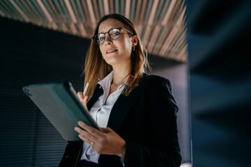Confident woman with tablet and stylus smiling gently, blending technology use and approachable attitude in modern mobile career © BullRun