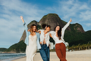 Three friends on a sunny beach with mountains