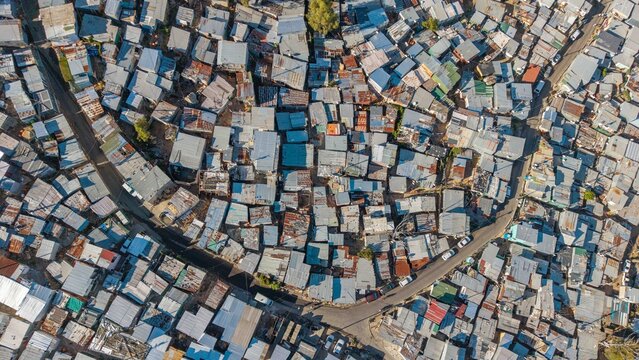 Aerial view of a dense patchwork of corrugated iron roofs tightly clustered together, divided by narrow pathways, Cape Town, Western Cape, South Africa.
