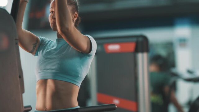 Strong muscular woman doing pull-ups in gym