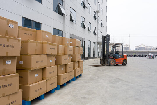 Forklift moving stacked cardboard boxes outside a warehouse facility