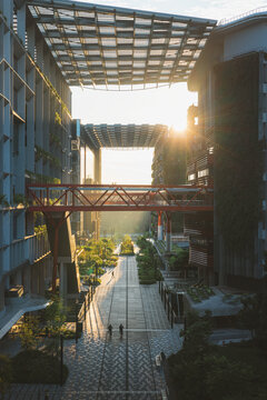 View of sunlight piercing through modern architecture, casting long shadows on the intricate ground designs in Punggol Coast Mall, Singapore.