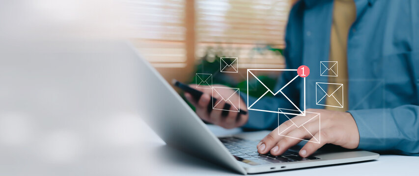Business professional working on laptop and smartphone with virtual email notification icons, concept of inbox email marketing, online communication, digital workflow and modern business technology.
