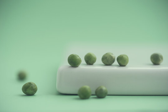 Close-up of Green peas on a ceramic plate on a green background
