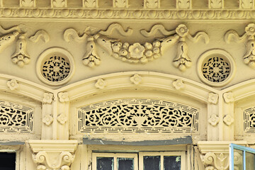 Obraz premium ornate architectural facade in Singapore, featuring a series of arched window transoms filled with intricate lattice work. 