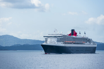 Modern cruise liner traveling across calm ocean waters under a clear blue sky, passenger vessel at sea.