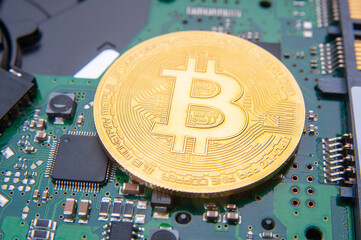 Golden bitcoin coin on a mainboard close up