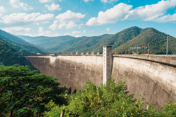 Large concrete dam landscape with mountain and forest hill in sunny day