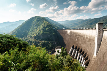 Large concrete dam landscape with mountain and forest hill in sunny day