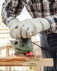 Craftsman. Adult carpenter using an electric sander to smooth an old wooden window. Construction...
