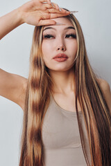 Young woman with long straight hair posing with hand on forehead looking thoughtful and relaxed...