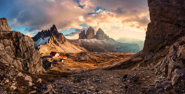 Golden hour panorama of Tre Cime di Lavaredo mountain peak with mountain hut during autumn in Dolomites, Italy