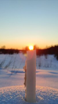 A candle burns at sunset