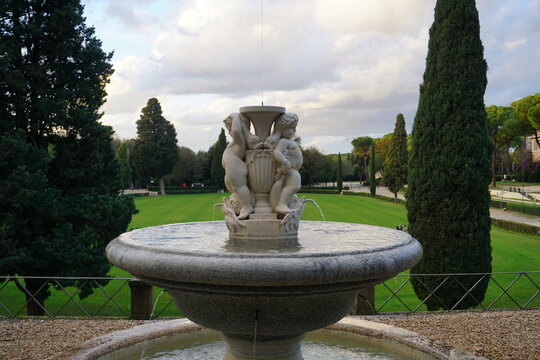 A beautiful water fountain with Renaissance angel statues or putti in the park of Villa Borghese in Rome, Italy