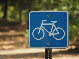 Blue bicycle trail sign on a blurred forest background