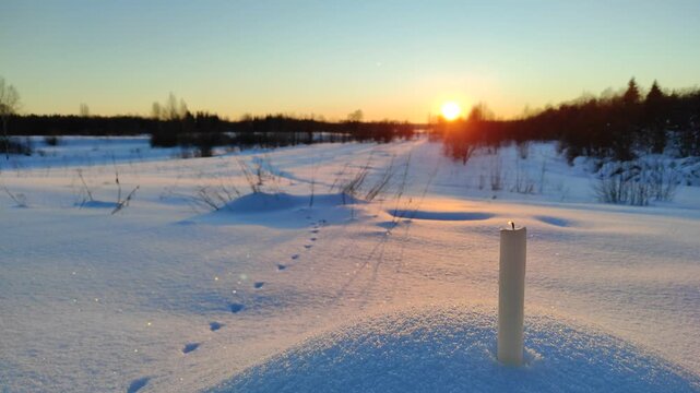 A candle burns at sunset