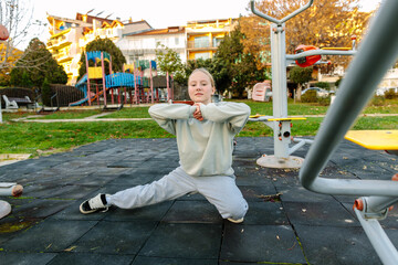 Teenage girl stretching legs on outdoor fitness playground, body control exercise, balance and flexibility training, healthy lifestyle, wellbeing and active childhood concept
