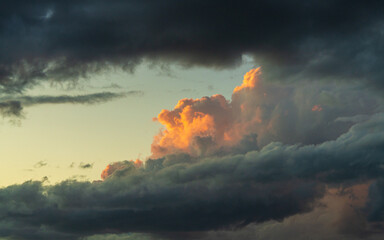 Obraz premium Dramatic evening sky with one cloud catching warm sunset light above dark storm background. Natural weather concept emphasizing light versus darkness.
