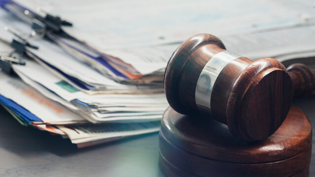 Stack of folders and a judge gavel on a desk
