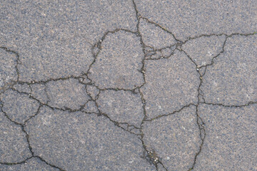 Fototapeta premium A cracked and broken pavement with a lot of holes and cracks