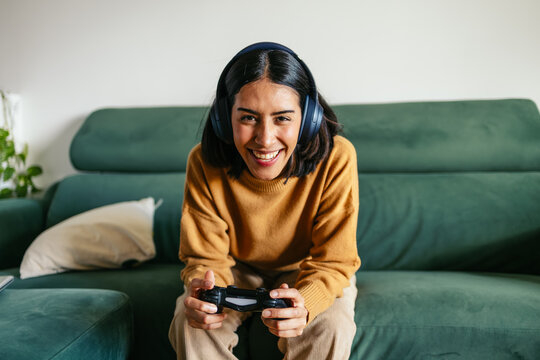 Young woman enjoying videogames playing with controller and headphones