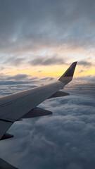 Fototapeta premium Airplane wing view during sunset flight above clouds traveling aviation concept of airlines, travel agencies, tourism companies