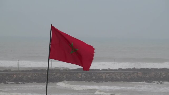 Rabat, Morocco A large red Moroccan flag flies over the Bab Oudayas,  Kasbah of the Udayas, on the Atlantic Ocean.